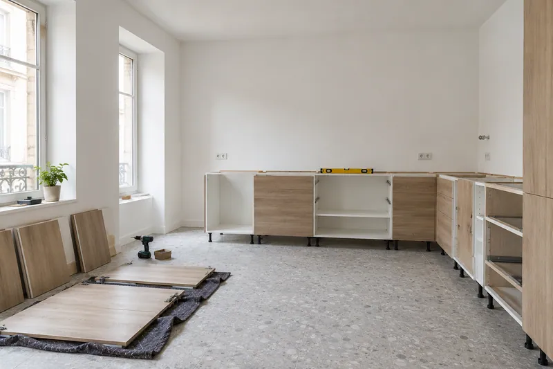 Visualización conceptual IA: Módulos de cocina en montaje con puertas pendientes de colocar.